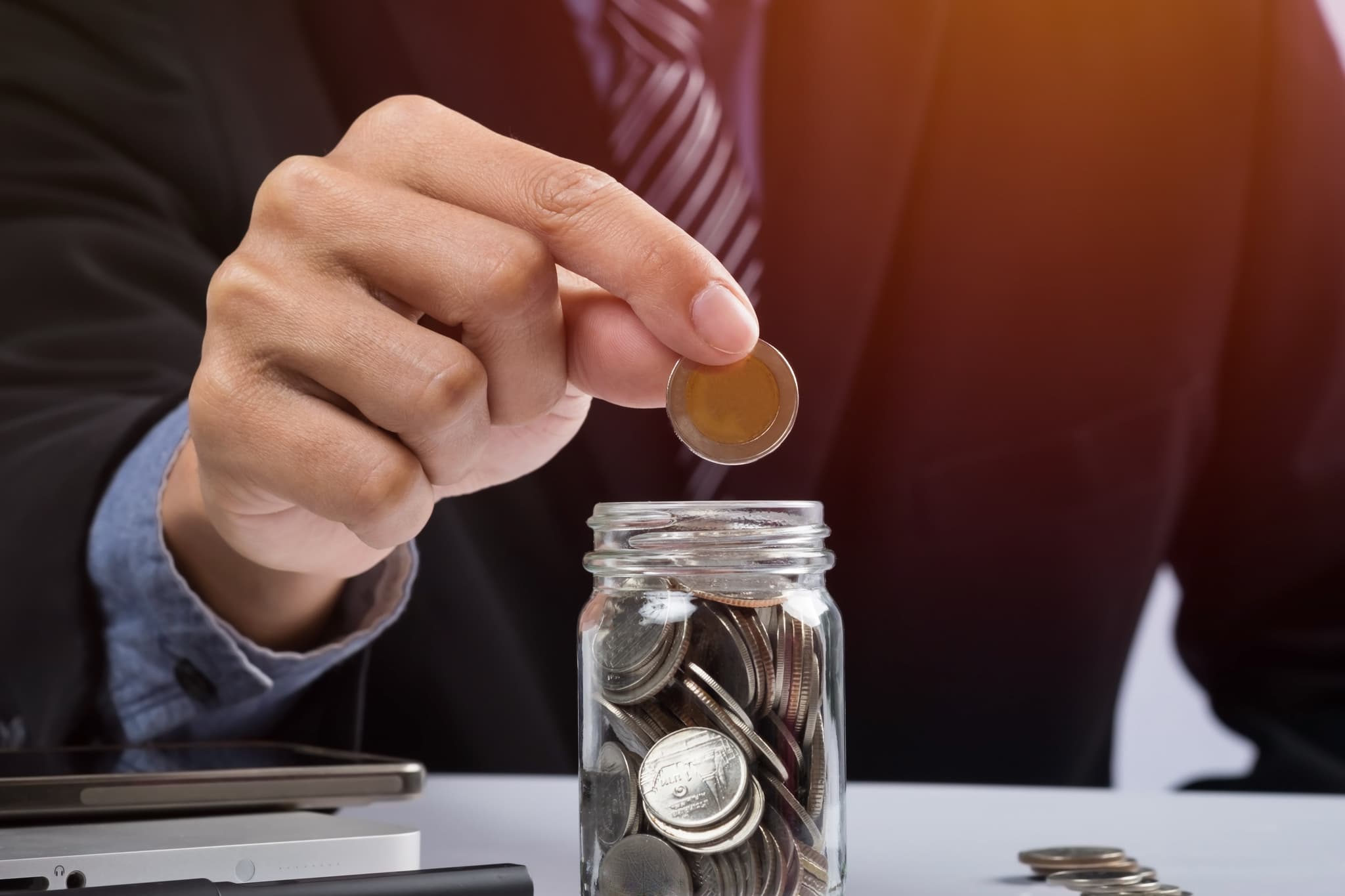 A man putting a coin in a jar